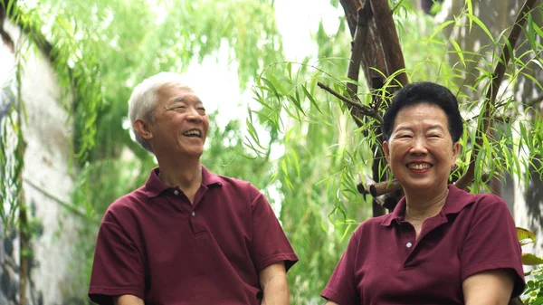 Happy retired Asian senior couple laughing under green willow tree background — Stock Photo, Image