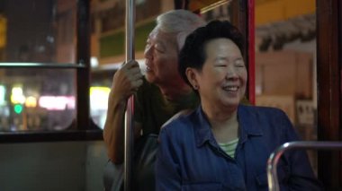 Asyalı yaşlı çift gece vakti Hong Kong tramvayında iyi yolculuklar.