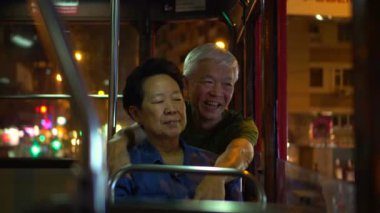 Asyalı yaşlı çift gece vakti Hong Kong tramvayında iyi yolculuklar.