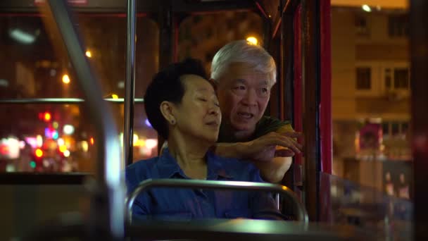 アジアの老夫婦は夜に香港シティトラムで楽しい旅行をしています — ストック動画