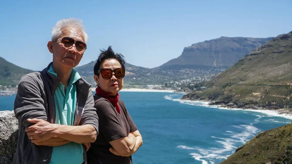 Asian senior couple travel anniversary trip in South Africa beautiful blue sea and sky beach coastline