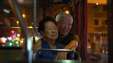 Asyalı yaşlı çift gece vakti Hong Kong tramvayında iyi yolculuklar.