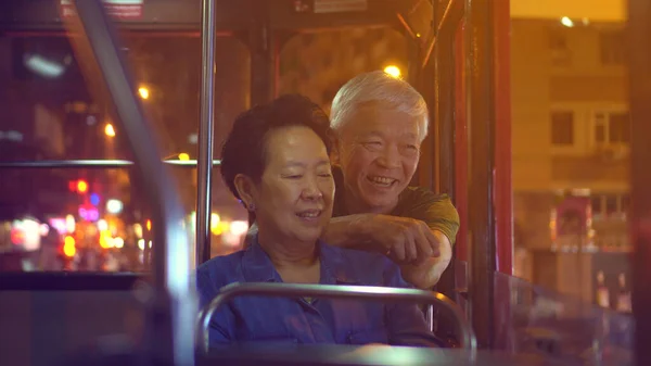 Asian elder couple have fun travel through Hong Kong city tram at night