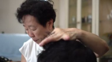 Asyalı anne, karantina sırasında oğlu için berber tıraşı yapıyor.