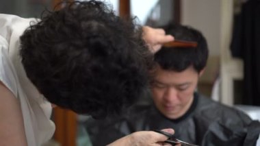 Asyalı anne, karantina sırasında oğlu için berber tıraşı yapıyor.