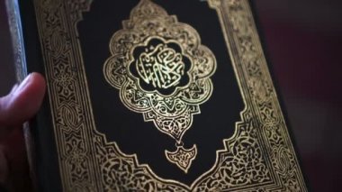 Güneş ışığı, Müslüman Kuran 'ın kutsal kitaplarının kapağına vuruyor. Parlak siyah ve altın renkli.