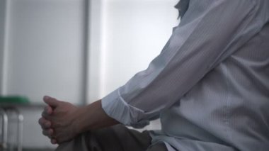 Yaşlı Asyalı adam hastanede tanımadığı insanları beklerken endişeleniyor.