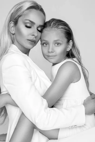 Vacker kvinna mor med dotter snuggling tillsammans och visa kärlek, snyggt klädd i en vit klänning — Stockfoto