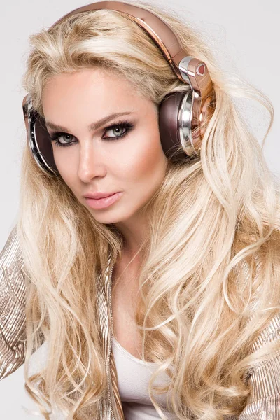 Güzel seksi sarışın kadın ile uzun saç ve kulaklık ile oturan altın ve gümüş kristalleri ile muhteşem elbise mükemmel vücut