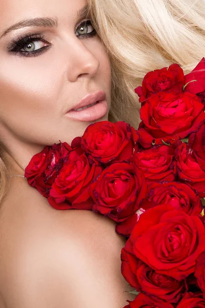 Πορτρέτο του όμορφη ξανθιά γυναίκα και φαίνεται καταπληκτικό και μακριά μαλλιά, τέλειο δέρμα, κρατά το πρόσωπό της ένα μπουκέτο από κόκκινα τριαντάφυλλα λουλούδια, valentine ημέρες — Φωτογραφία Αρχείου