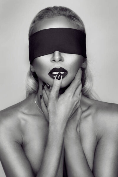 Красивая чувственная женщина модель с красными губами и ногтями связан, покрытые глаза ободок и выглядит эротически
