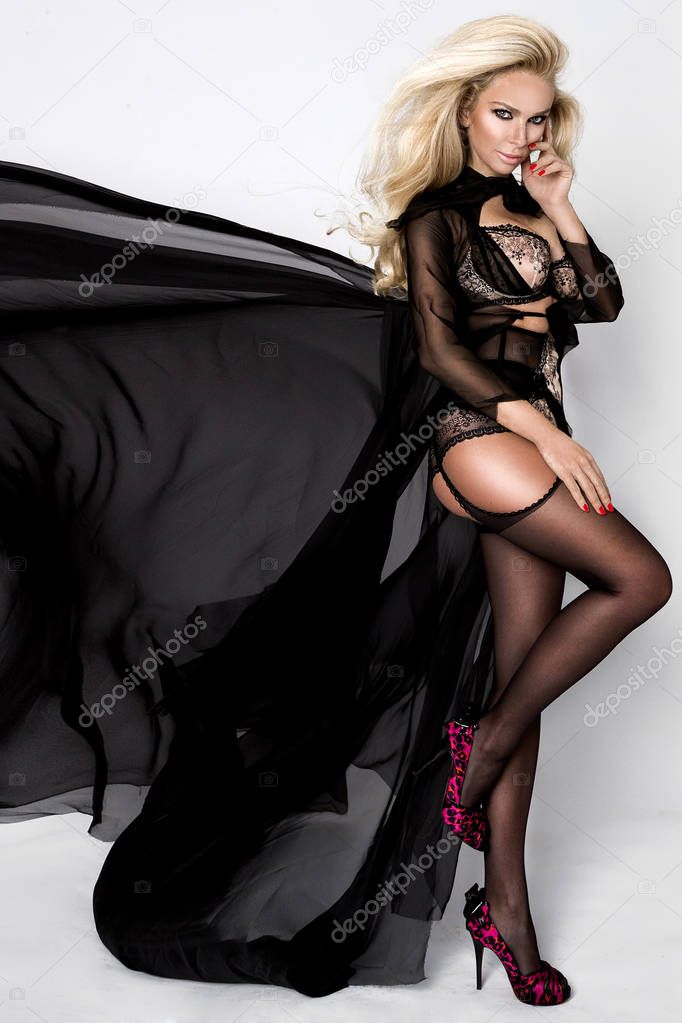 Beautiful blonde woman model with disheveled long hair and dispelled black silk dress