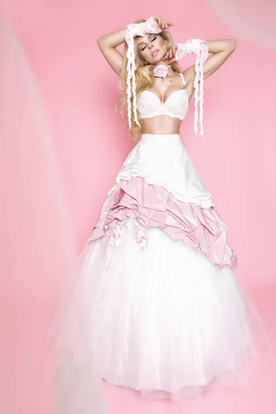 Hermosa modelo femenina rubia en un vestido de novia sobre un fondo rosa — Foto de Stock