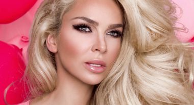 Pembe bir arka plan ve sevinçle gülümsüyor üzerinde pembe elbise duran uzun sarı saçlı güzel kadın modeli giymiş