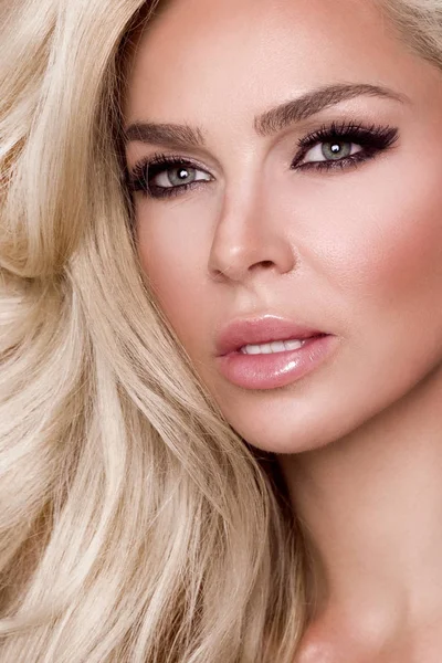 Pembe bir arka plan ve sevinçle gülümsüyor üzerinde pembe elbise duran uzun sarı saçlı güzel kadın modeli giymiş