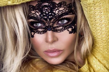 Karnaval maskesi yüzünde şehvetli sarışın kadınla güzel bir siyah arka plan üzerinde duruyor ve seksi lense benziyor