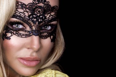 Karnaval maskesi yüzünde şehvetli sarışın kadınla güzel bir siyah arka plan üzerinde duruyor ve seksi lense benziyor