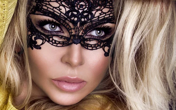 Karnaval maskesi yüzünde şehvetli sarışın kadınla güzel bir siyah arka plan üzerinde duruyor ve seksi lense benziyor