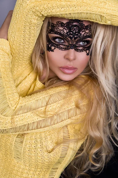 Karnaval maskesi yüzünde şehvetli sarışın kadınla güzel bir siyah arka plan üzerinde duruyor ve seksi lense benziyor