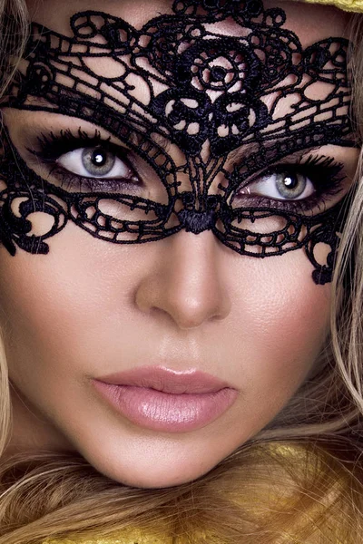 Gyönyörű érzéki szőke nő arcán karneváli maszk áll egy fekete háttér és a szexi néz a kamerába — Stock Fotó