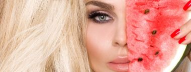 Bir karpuz yüzüne tutarak uzun sarı saçlı güzel kadın modeli