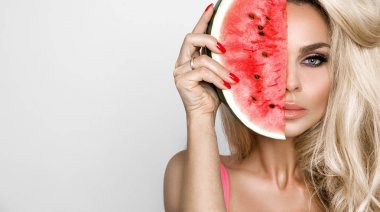 Bir karpuz yüzüne tutarak uzun sarı saçlı güzel kadın modeli