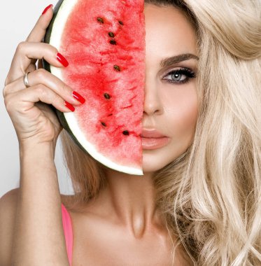 Bir karpuz yüzüne tutarak uzun sarı saçlı güzel kadın modeli