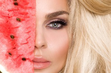 Bir karpuz yüzüne tutarak uzun sarı saçlı güzel kadın modeli
