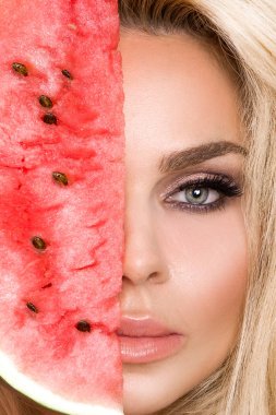 Bir karpuz yüzüne tutarak uzun sarı saçlı güzel kadın modeli