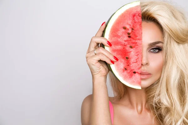 Modelo feminino bonita com cabelo loiro longo, segurando uma melancia em seu rosto — Fotografia de Stock