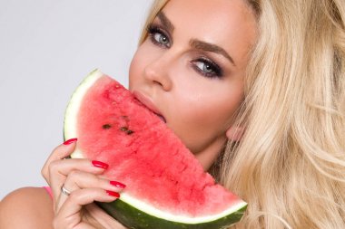 Bir karpuz yüzüne tutarak uzun sarı saçlı güzel kadın modeli