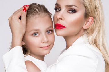 Beyaz bir arka plan üzerinde duran sevimli sarışın kızı olan genç bir anne güzellik çarpıcı bir bahar kılığına girmiş