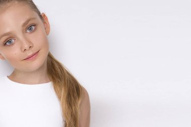 Güzel sarışın genç model, beyaz bir arka plan üzerinde beyaz elbiseli sevimli kız. Zarif küçük kız