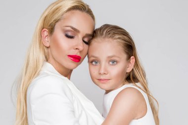 Beyaz bir arka plan üzerinde duran sevimli sarışın kızı olan genç bir anne güzellik çarpıcı bir bahar kılığına girmiş