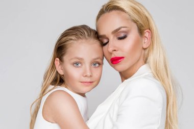 Beyaz bir arka plan üzerinde duran sevimli sarışın kızı olan genç bir anne güzellik çarpıcı bir bahar kılığına girmiş