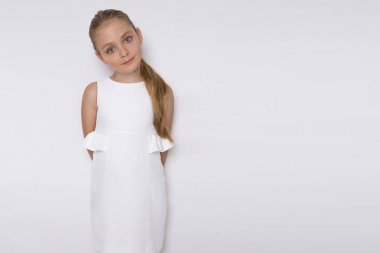 Güzel sarışın genç model, beyaz bir arka plan üzerinde beyaz elbiseli sevimli kız. Zarif küçük kız