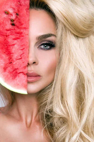 Modelo feminino bonita com cabelo loiro longo, segurando uma melancia em seu rosto — Fotografia de Stock