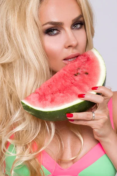 Bir karpuz yüzüne tutarak uzun sarı saçlı güzel kadın modeli
