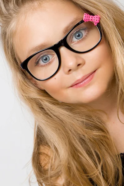 Portrait of a lovely little girl daughter in long blond hair and black glasses with pink bow which looks at the camera, photo on the white background ammazing eyes — Stock Photo, Image