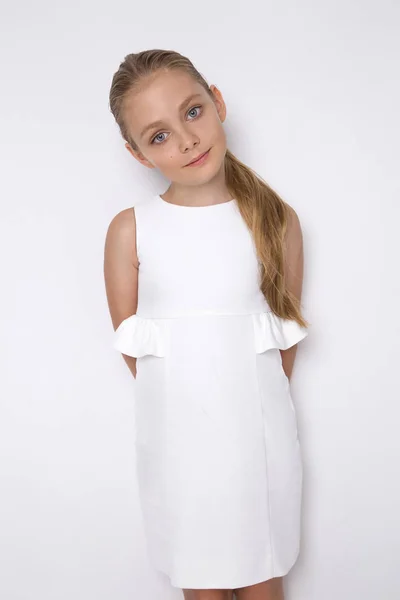 Hermosa rubia joven modelo, linda chica, en vestido blanco sobre un fondo blanco. Niña elegante — Foto de Stock