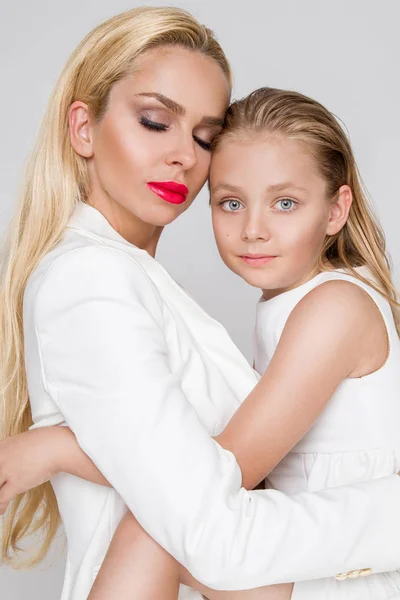 Потрясающая красота молодая мать с симпатичной блондинкой дочь стоит на белом фоне, одетый в весеннюю одежду — стоковое фото