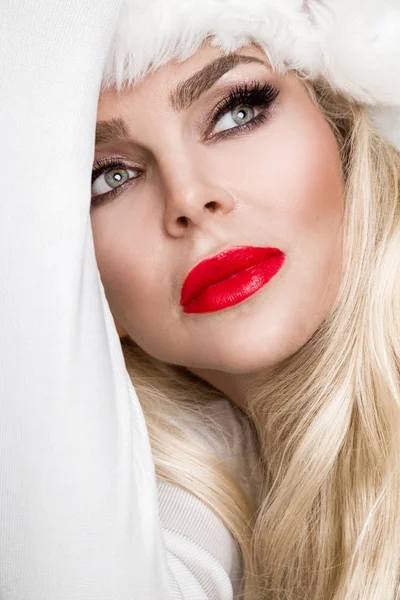 Mooie sexy blonde vrouwelijke model verkleed als Santa Claus in een rode dop met op de witte vacht mooie make-up sensuele lippen, Kerstmis — Stockfoto