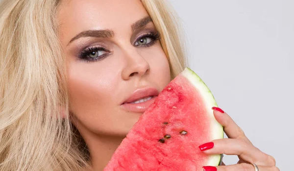 Bir karpuz yüzüne tutarak uzun sarı saçlı güzel kadın modeli