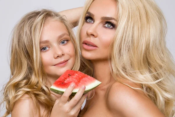 Hermosa modelo rubia, madre con abrazo de hija rubia. Sostienen la sandía y animan alegremente — Foto de Stock