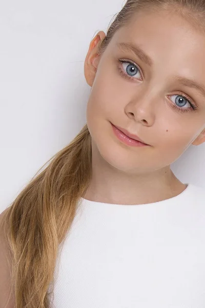 Retrato de una encantadora hija niña en pelo largo y rubio y vestido blanco mira a la cámara, foto sobre el fondo blanco ojos increíbles — Foto de Stock