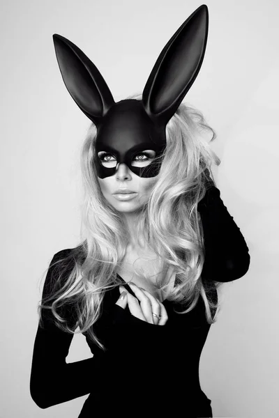 Sexy Frau mit großen Brüsten trägt eine schwarze Maske Osterhase steht auf weißem Hintergrund und sieht sehr sinnlich — Stockfoto