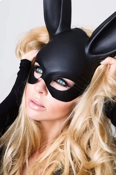 Sexy woman with large breasts wearing a black mask Easter bunny standing on a white background and looks very sensually — Stock Photo, Image