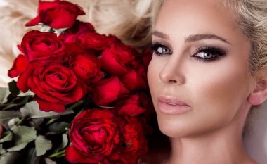 Güzel seksi sarışın beyaz bir arka plan üzerinde zarif iç çamaşırı. Bir buket kırmızı gül tutan kız.