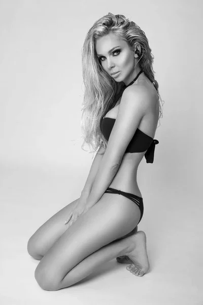 Bella donna sexy formosa bionda con i capelli lunghi in bikini nero su uno sfondo bianco, ha il corpo geourgeus, viso perfetto, glutei in foto in bianco e nero — Foto Stock