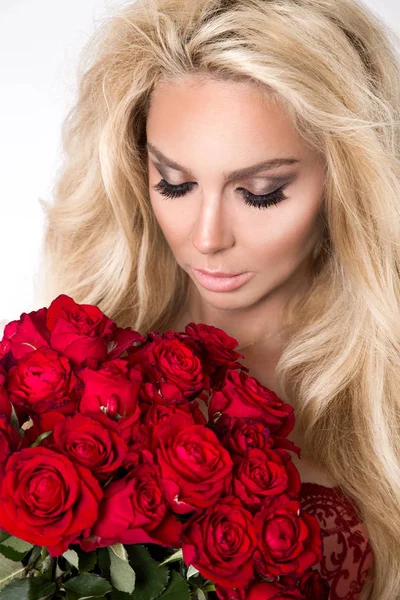 Gyönyörű szőke elegáns fehérnemű-fehér alapon. Lány, kezében egy csokor vörös rózsa. — Stock Fotó